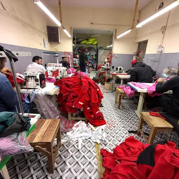 Skilled craftsmen operating industrial sewing machines on the apparel factory floor during high-volume hoodie production